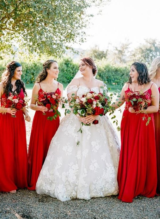 matching red maxi bridesmaid dresses with spaghetti straps and pleated skirts for a wedding infused with red