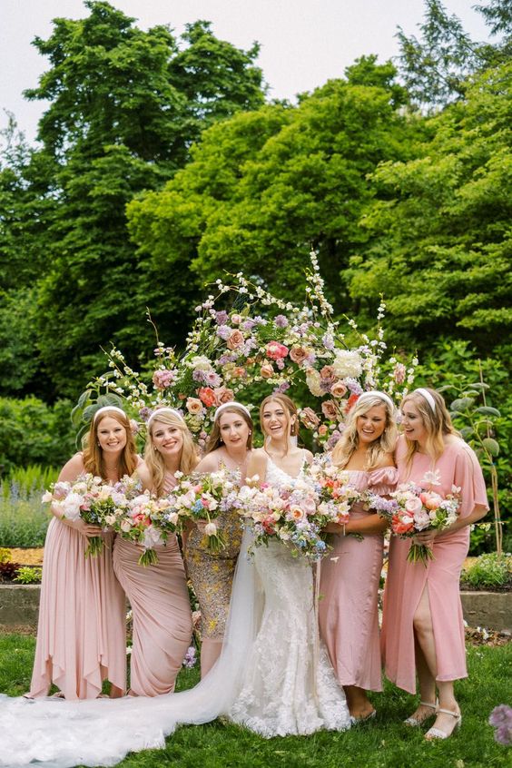 mix and match light pink mid and maxi bridesmaid dresses with slits and draping plus white heels for a garden wedding