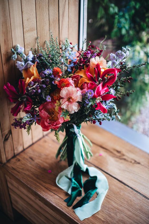 a colorful-infused wedding bouquet of orange, lilac, purple, fuchsia and pink blooms and some blooming branches