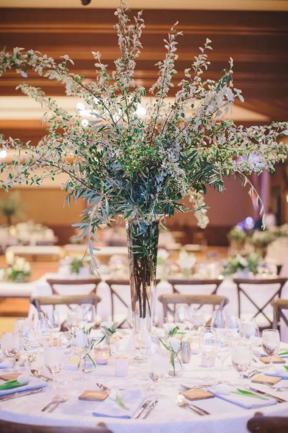 a lovely long-stemmed wedding centerpiece of greenery and some blooming branches for a spring wedding