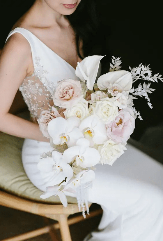 a chic cascading wedding bouquet of blush and light pink roses, white anthurium and orchids plus some white grasses