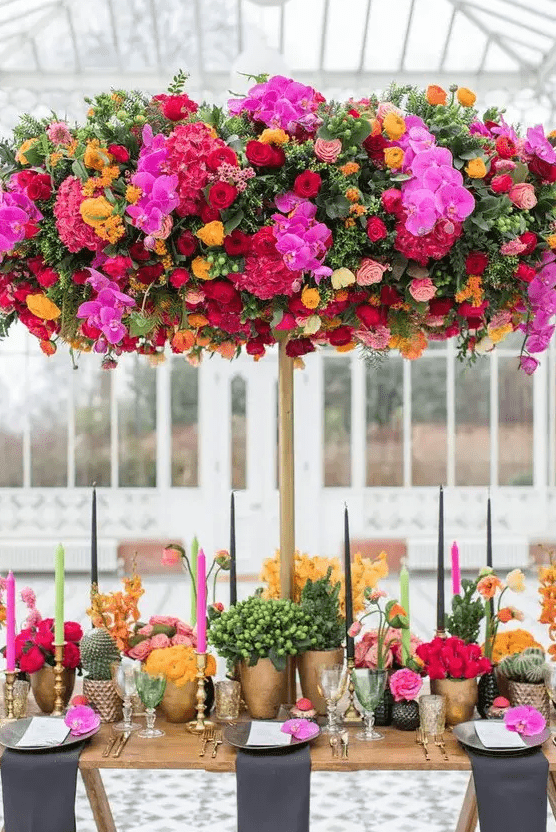 a fantastic colorful overhead wedding installation with hot pink, burgundy, yellow and pink blooms and greenery is wow