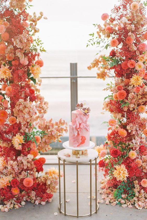 a sunset-colored floral installation to accent the wedding cake is an adorable idea to rock, it looks amazing
