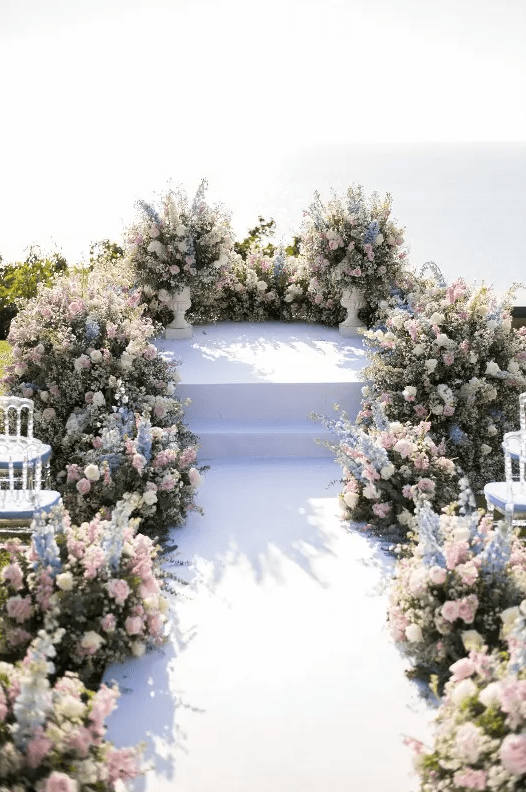 a beautiful pastel wedding ceremony space is amazing with pink, blue and white blooms and greenery is gorgeous