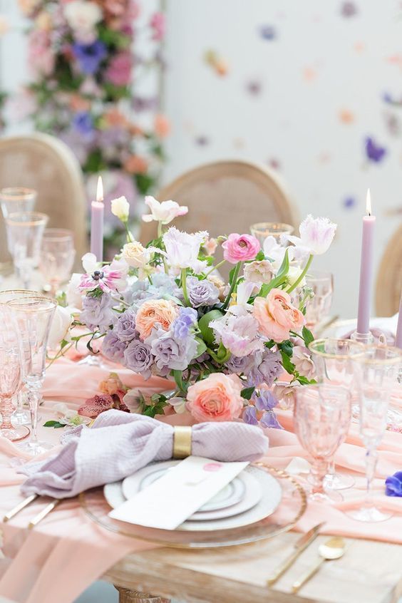 a beautiful spring wedding centerpiece of pink, lilac and peachy blooms and greenery is amazing
