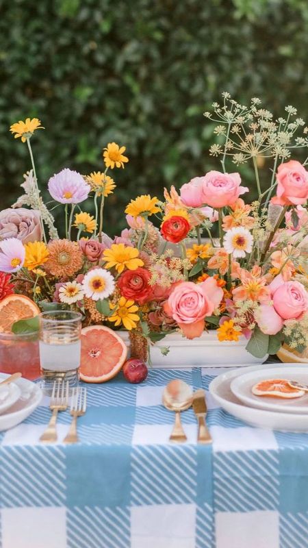 a bright summer wedding centerpiece of yellow, orange, pink, peachy and coral flowers and foliage is amazing