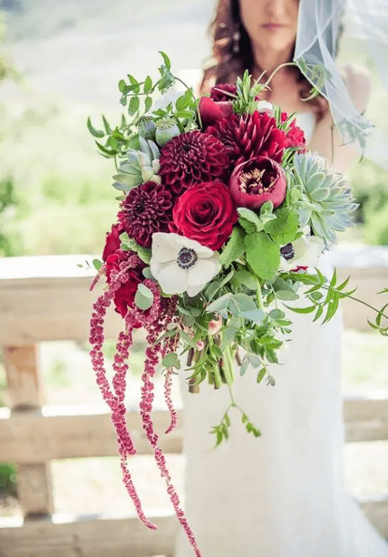 a bright wedding bouquet of burgundy mums, roses and peonies, a white anemone, greenery and amaranthus for the fall