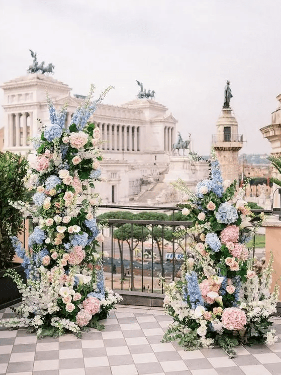 a charming wedding altar with blue and blush hydrangeas, blush roses and delphinium plus greenery and iconic Rome views