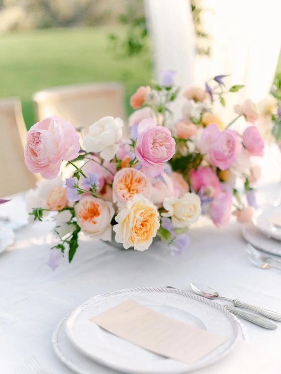 a chic pastel wedding centerpiece of pink, peachy, periwinkle flowers and greenery is a lovely idea for spring and summer