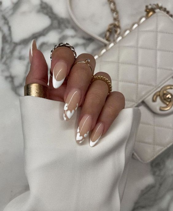 a classy French manicure with two accent nails done with white hearts is a very playful and cute solution