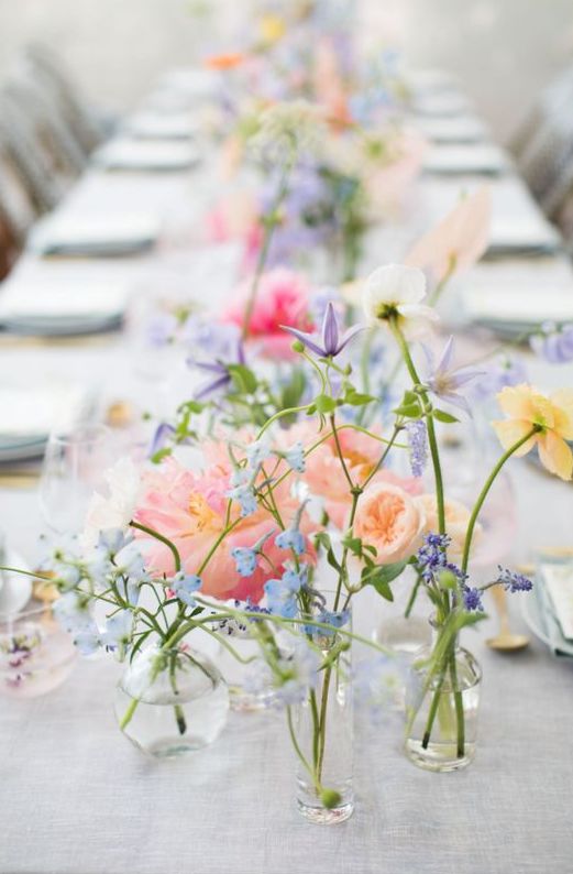 a classy cluster wedding centerpiece of pastel peachy, pink, lilac and blue flowers in separate vases is wow