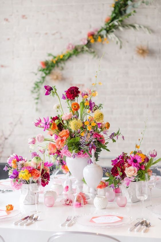 a colorful cluster wedding centerpiece including yellow, orange, hot pink and red blooms and greenery
