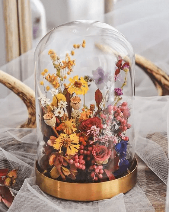 a colorful dried flower wedding centerpiece with pink, red, purple and yellow blooms and seed pods