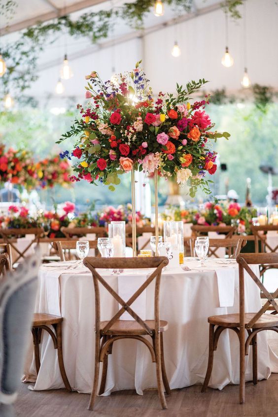 a colorful tall wedding centerpiece of blush, hot pink, red, fuchsia, violet flowers and greenery for summer