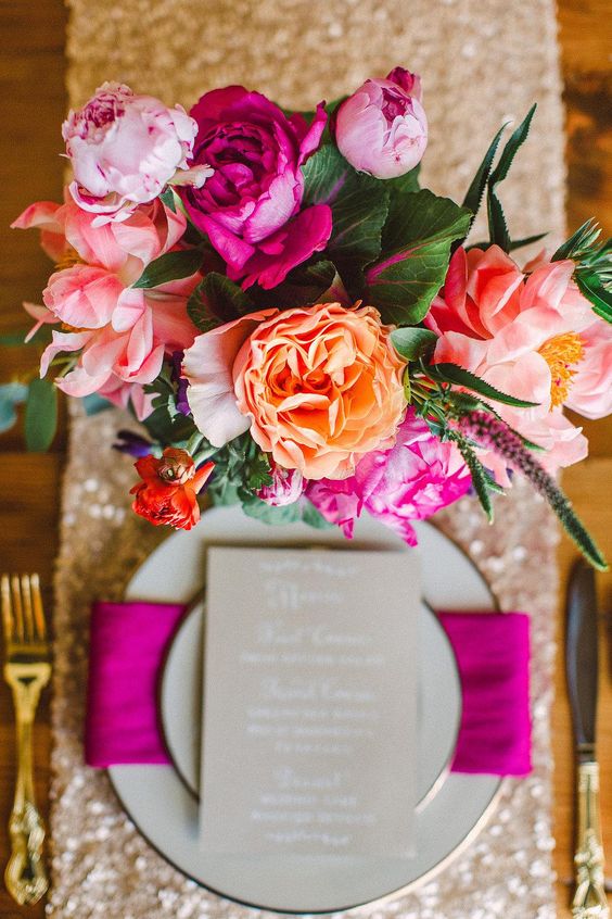 a colorful wedding centerpiece of orange, light and hot pink blooms, astilbe and greenery for a bold wedding
