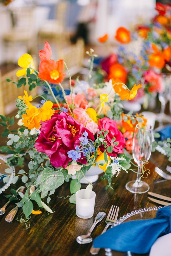 a colorful wedding centerpiece of yellow, coral, hot pink and fuchsia flowers and foliage is amazing for summer