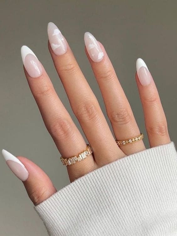 a cute French manicure with two accent nails that show a cloudy and starry sky in the same classic French colors