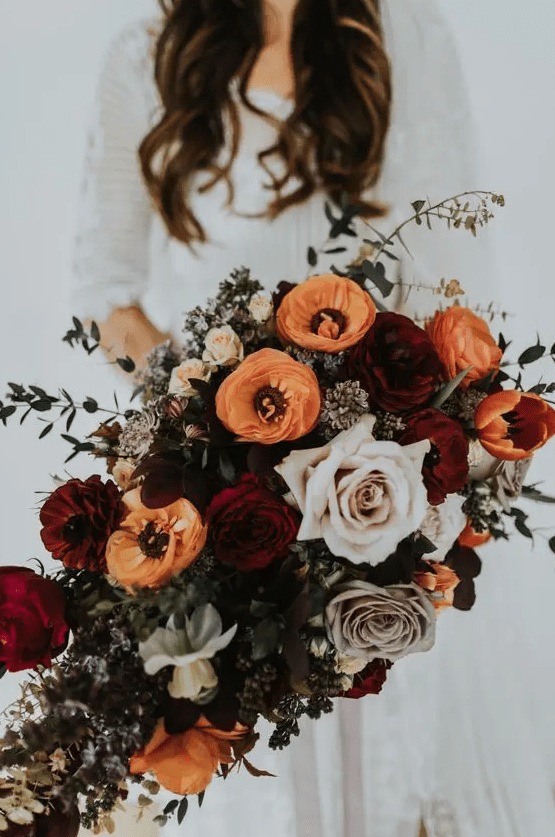 a dimensional fall wedding bouquet of orange, burgundy, lilac and pale pink blooms, greenery is a lovely idea for a bold or moody fall wedding