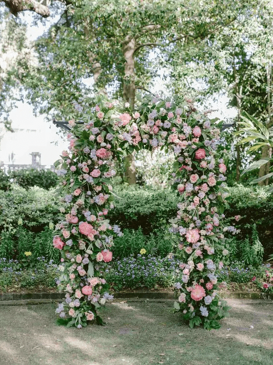 a dreamy pastel wedding arch decorated with greenery, pink peonies, blush roses and lilac blooms is a lovely idea for spring