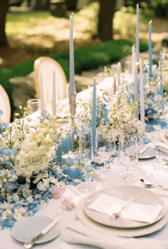 a fabulous wedding tablescape done with pastel blooms, pastel blue candles, neutral porcelain and neutral linens for a Bridgerton wedding