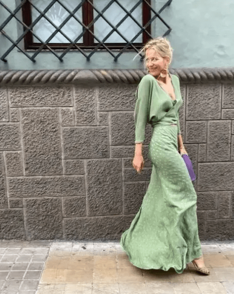 a lovely guest ensemble with a green wrap up blouse, a green printed maxi skirt, gold shoes and a purple clutch