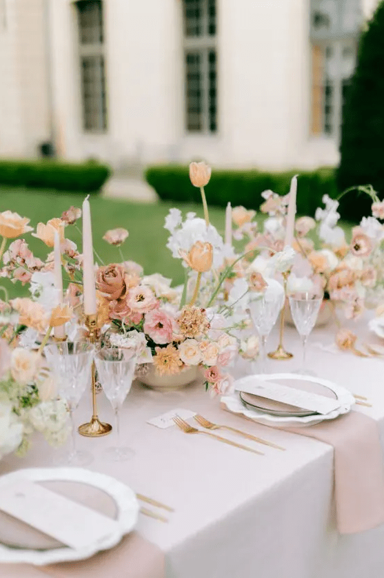 a lovely pastel spring wedding tablescape with blush linens, white, blush and yellow blooms and pink candles is chic