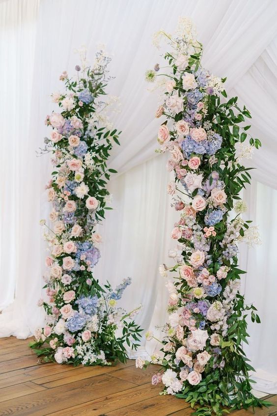 a lovely pastel wedding altar of greenery, blush and white roses and blue and periwinkle hydrangeas is amazing for spring