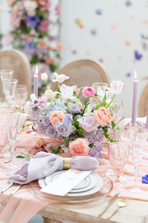 a lovely pastel wedding centerpiece of peachy, pink and lilac blooms and greenery for a spring wedding