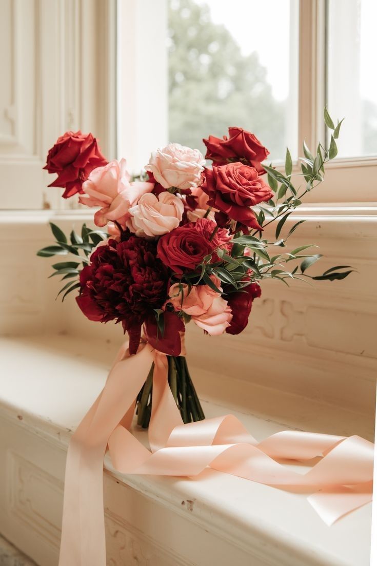 a lovely wedding bouquet of burgundy and deep red roses and peonies and blush blooms plus some greenery is amazing