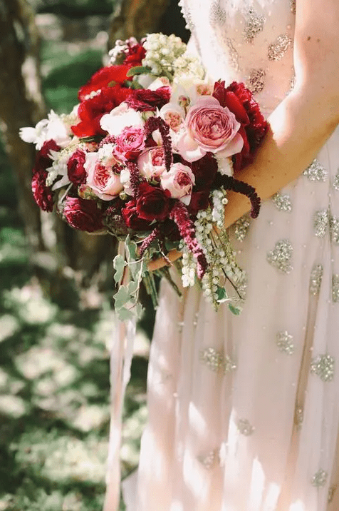a lush fall wedding bouquet in crimson, burgundy and blush and a blush glitter dress