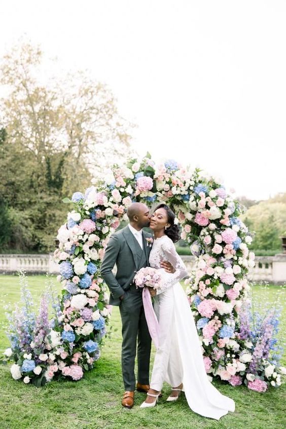 a lush wedding arch with pink and blus hydrangeas, white roses and greenery is a stunning idea for a spring wedding