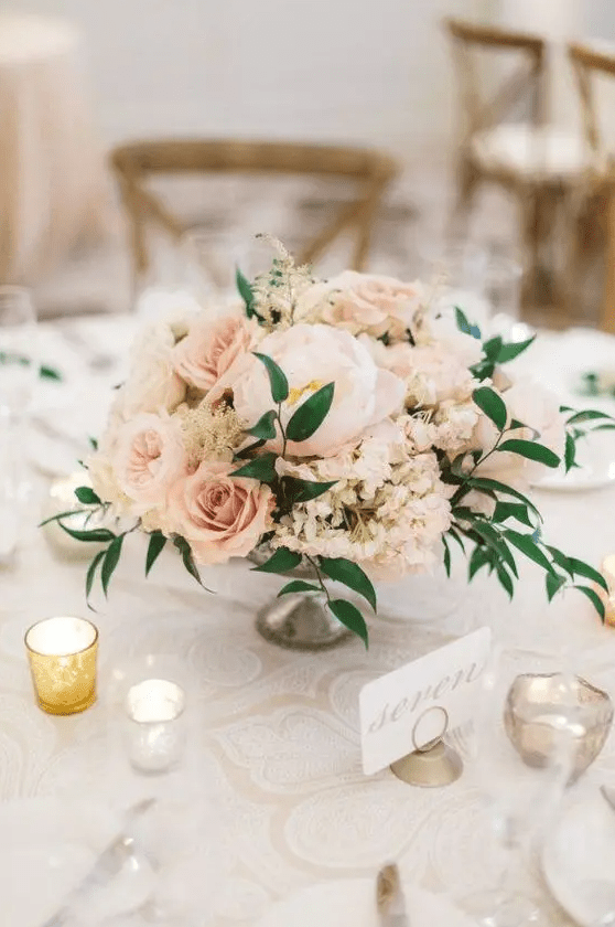 a pastel blush floral centerpiece with a couple of greenery touches looks very delicate and soft