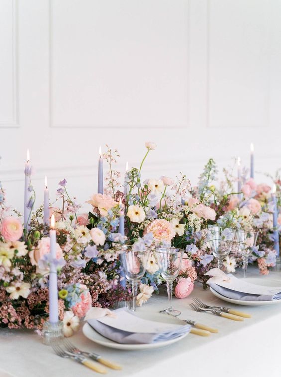 a pastel wedding centerpiece of lush blooms in blush, serenity blue and periwinkle blooms and matchines candles