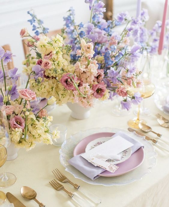 a pastel wedding centerpiece of pink, yellow, blue and lilac blooms is a lovely idea for a spring wedding