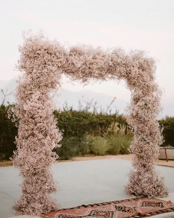 a pink baby's breath wedding arch is a cool and pastel wedding decor idea, just take baby's breath and spray paint it