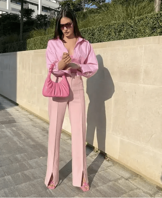 a pink guest outfit with a top, an oversized shirt, high waisted pants with slits, pink shoes and a small bag