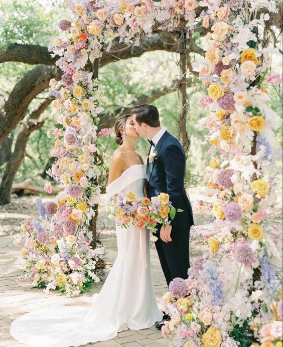 a pretty pastel wedding arch dotted with bold yellow blooms looks tender yet eye-catchy and quite bright