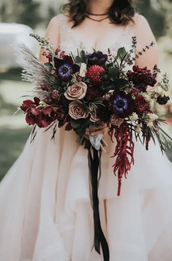 a refined moody wedding bouquet with pink purple, dusty pink, blue, red flowers, greenery and grasses is very chic