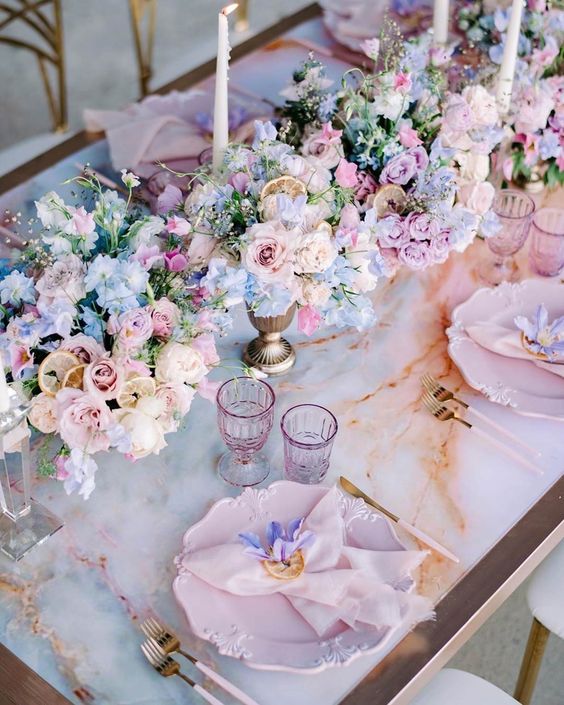 a row of sophisticated wedding centerpiece of pastel blue, blush and lilac blooms and candles is a lovely idea for spring