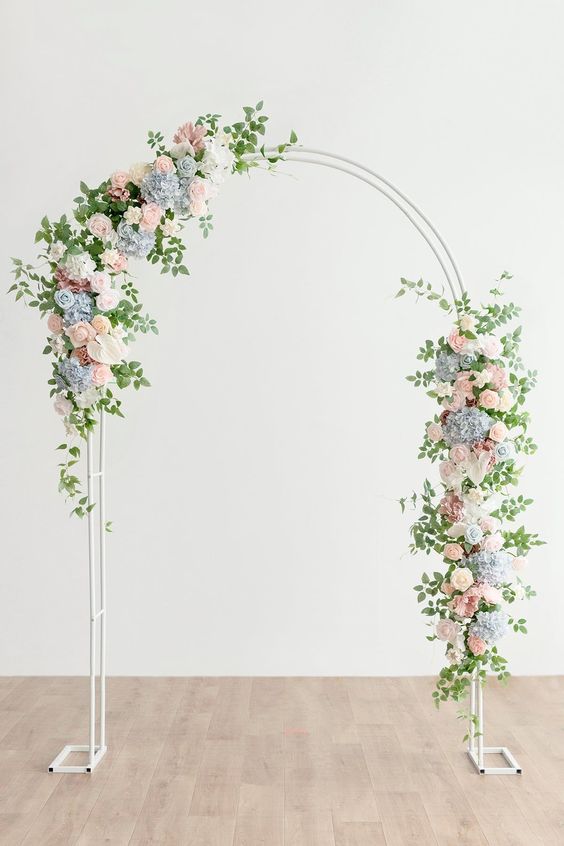a simple and cool wedding arch with blue hydrangeas, blush and white roses and greenery is a cool idea for spring