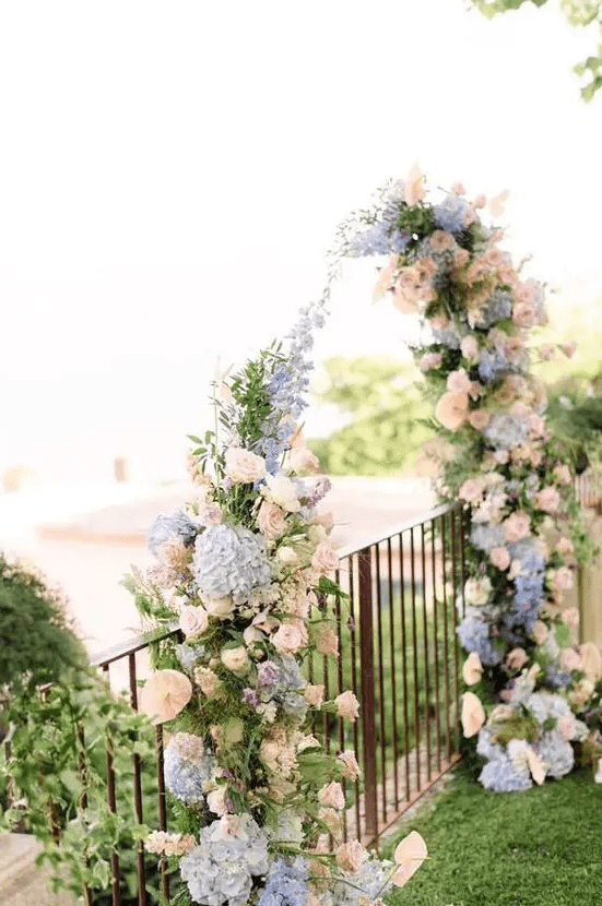 a simple floral wedding arch of blush, pink and blue blooms is a very pretty and delicate idea suitable for a garden wedding