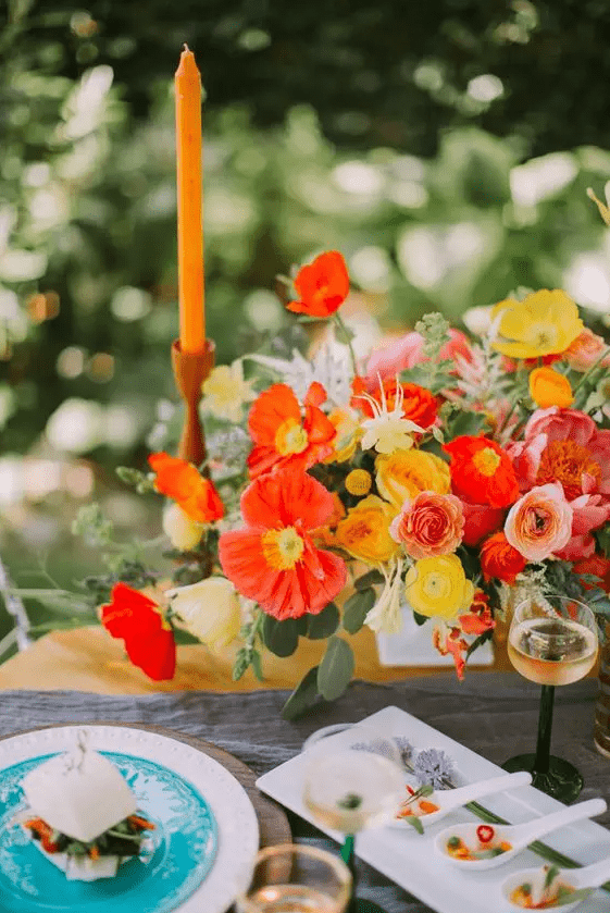 a super bright poppy wedding centerpiece of red and yellow poppies and ranunculus is amazing for a bright summer wedding