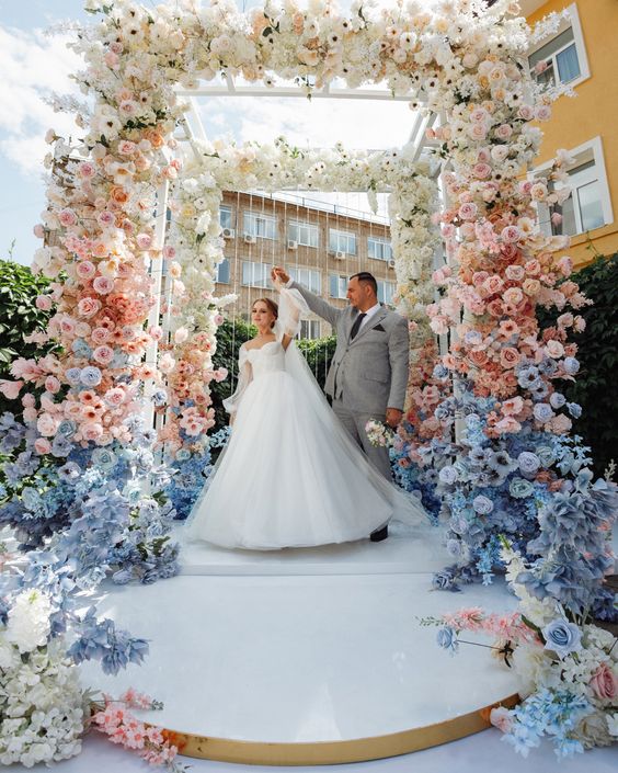 a super lush pastel wedding arch covered with white, pink and serenity blue flowers creating an ombre effect
