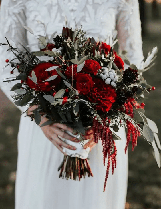 a traditional Christmas wedding bouquet of red, burgundy blooms, berries and greenery plus twigs