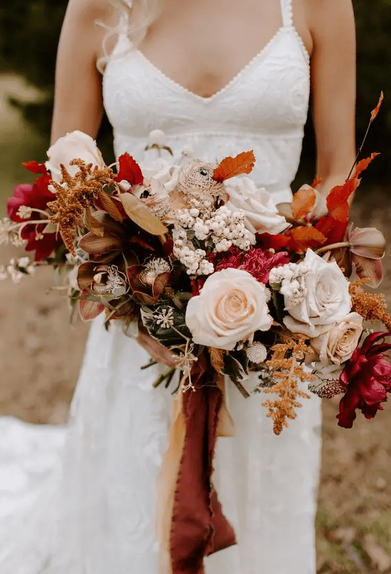 a vibrant fall wedding bouquet of fuchsia, blush, rust blooms, berries, dark foliage and matching ribbons is great for a boho wedding