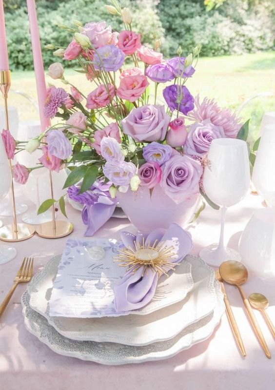 a whimsical wedding centerpiece of pastel pink, lilac and violet blooms arranged in an asymmetrical way
