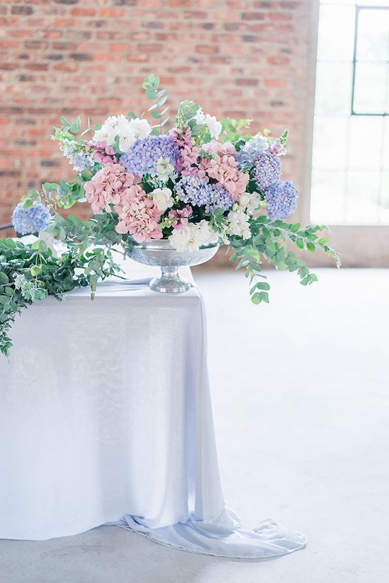 an amazing pastel spring wedding centerpiece of lilac and pink hydrangeas plus white ones and greenery