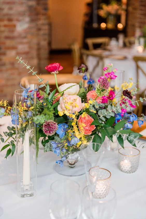 an eye-catchy and bold wedding centerpiece of blush, coral, pink, blue and yellow flowers and foliage is amazing for summer
