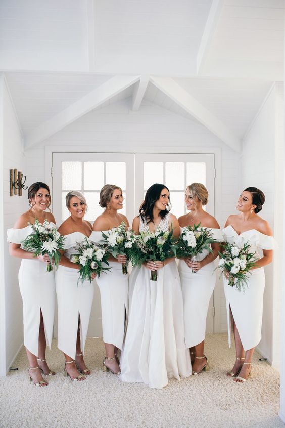 elegant modern white off the shoulder midi bridesmaid dresses with slits and silver shoes for a summer wedding