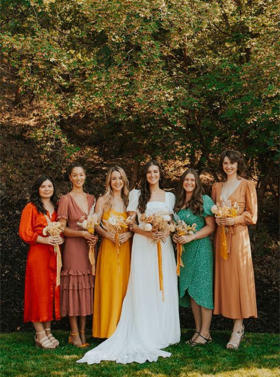 mismatching colorful bridesmaid dresses of solid color and with prints, with various designs for a bright wedding